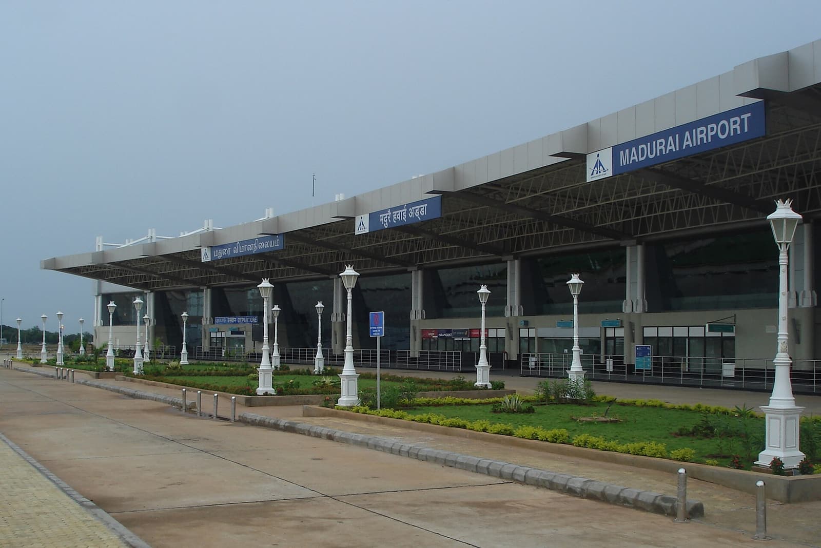 The terminal building of Madurai Airport with its name sign, seen across the forecourt gardens