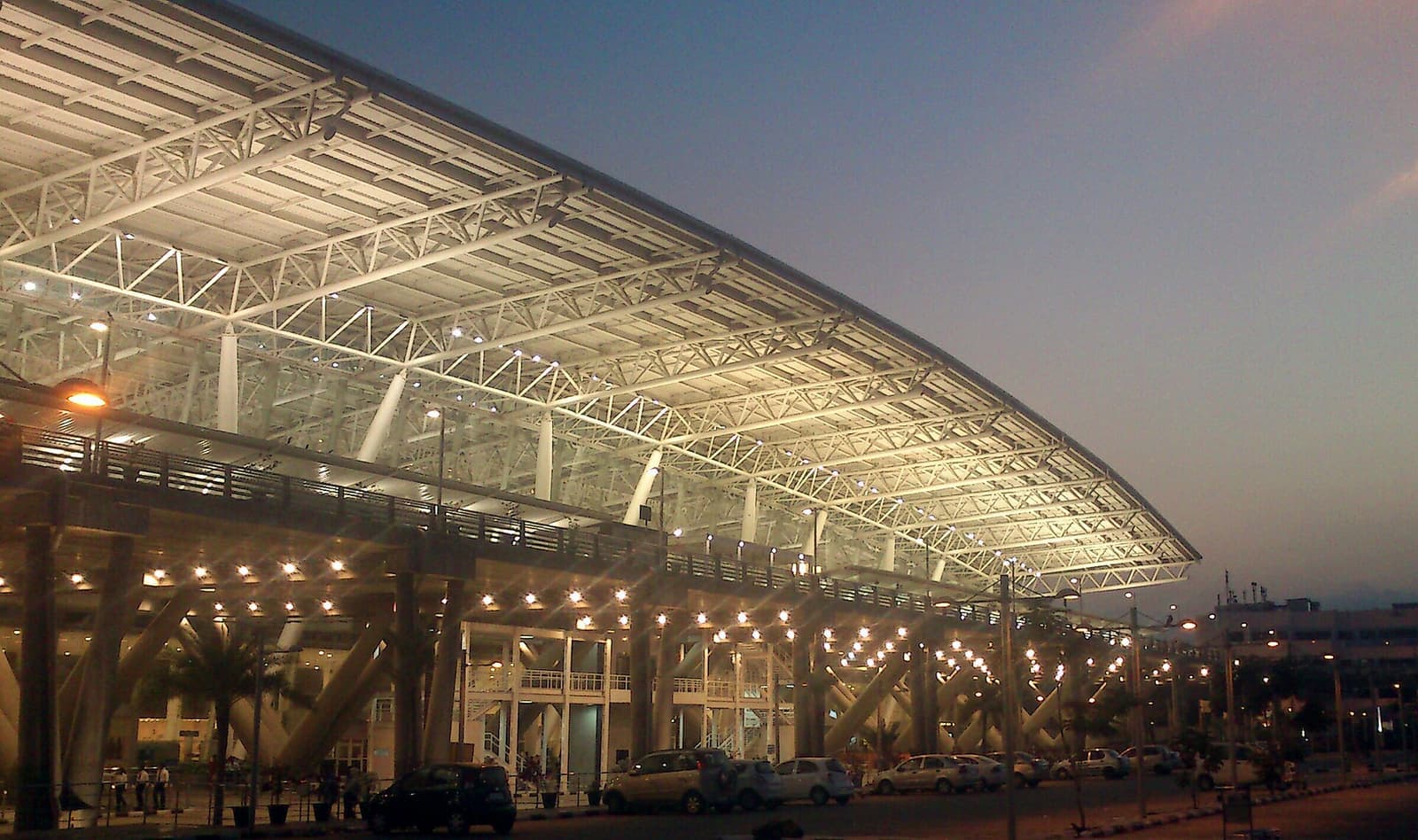 The glass-and-steel terminal roof of Chennai International Airport lit up at dusk