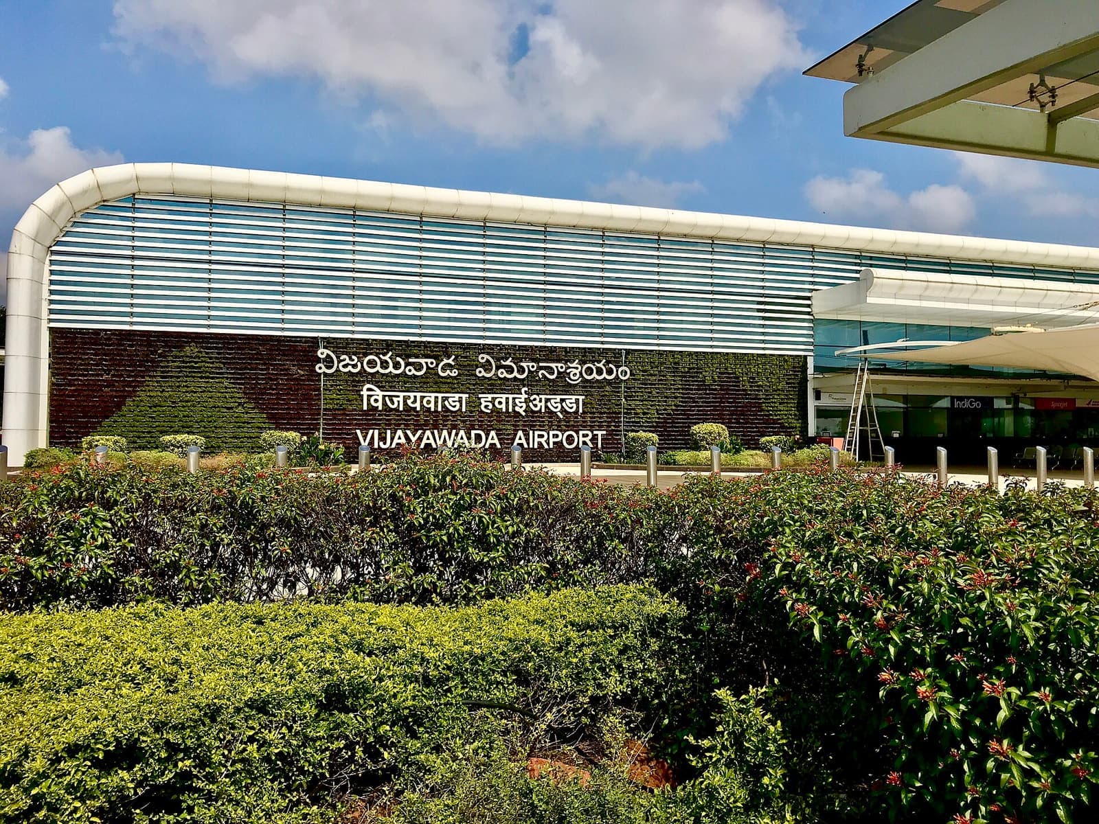 The Vijayawada Airport name sign in a hedge in front of the terminal building