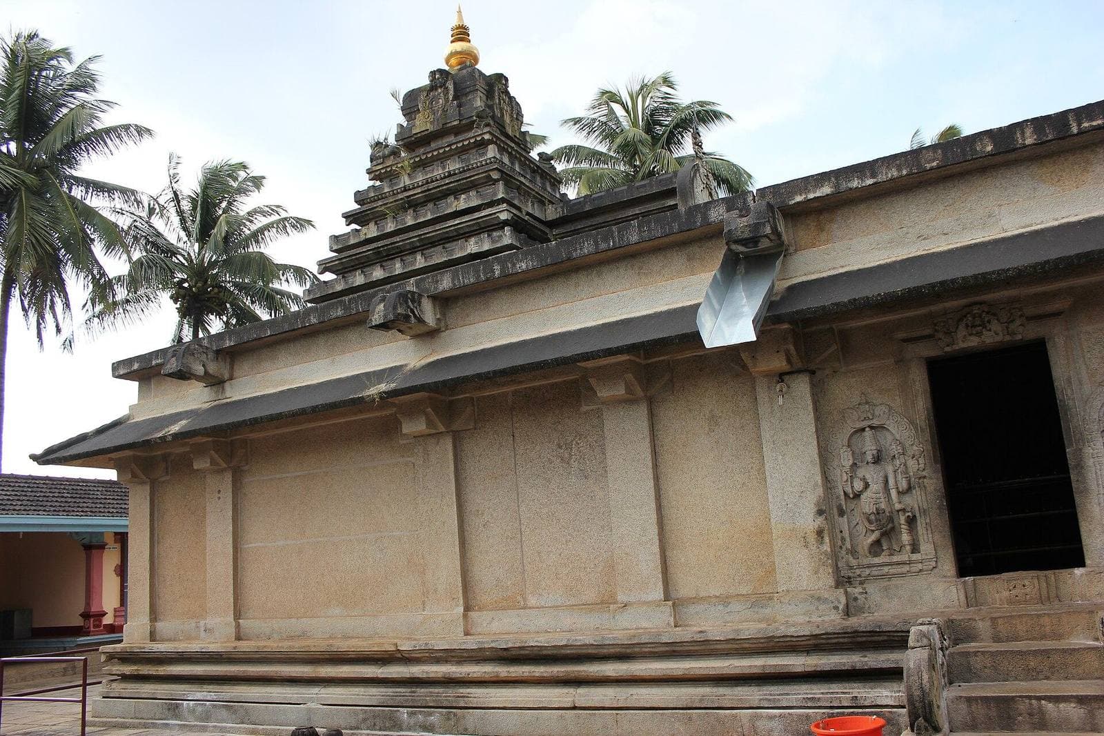 A stone temple in Chikkamagaluru framed by palm trees
