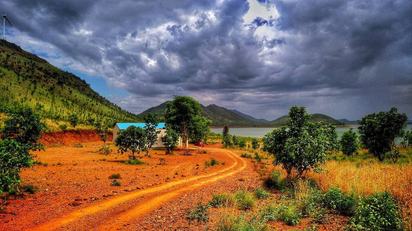 Red earth, trees and hills under a dramatic sky near Chitradurga
