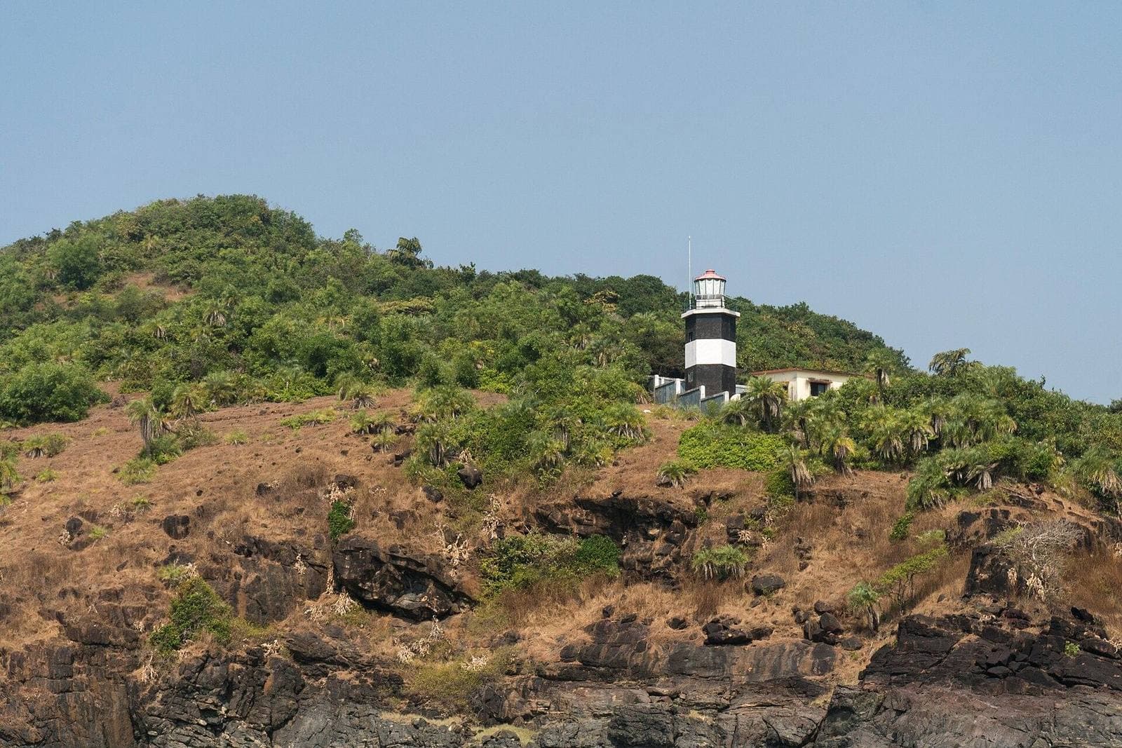 A green headland and lighthouse above the sea at Gokarna