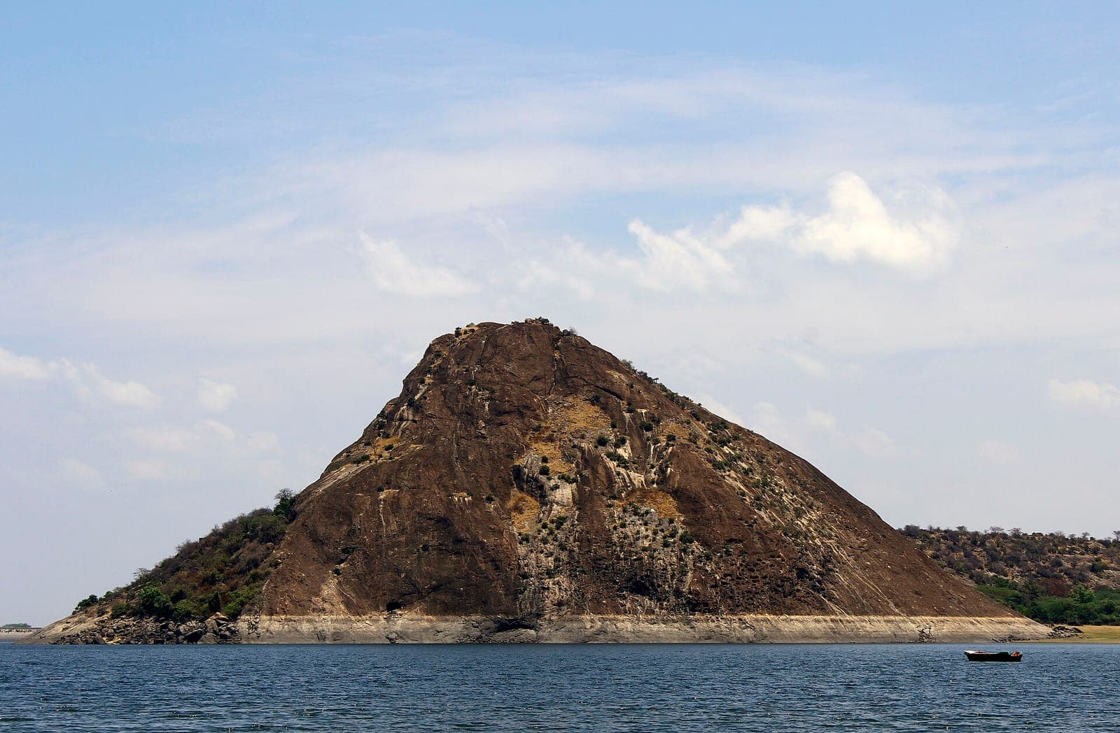 A rocky hill of the Thirumoorthy Hills rising above the reservoir