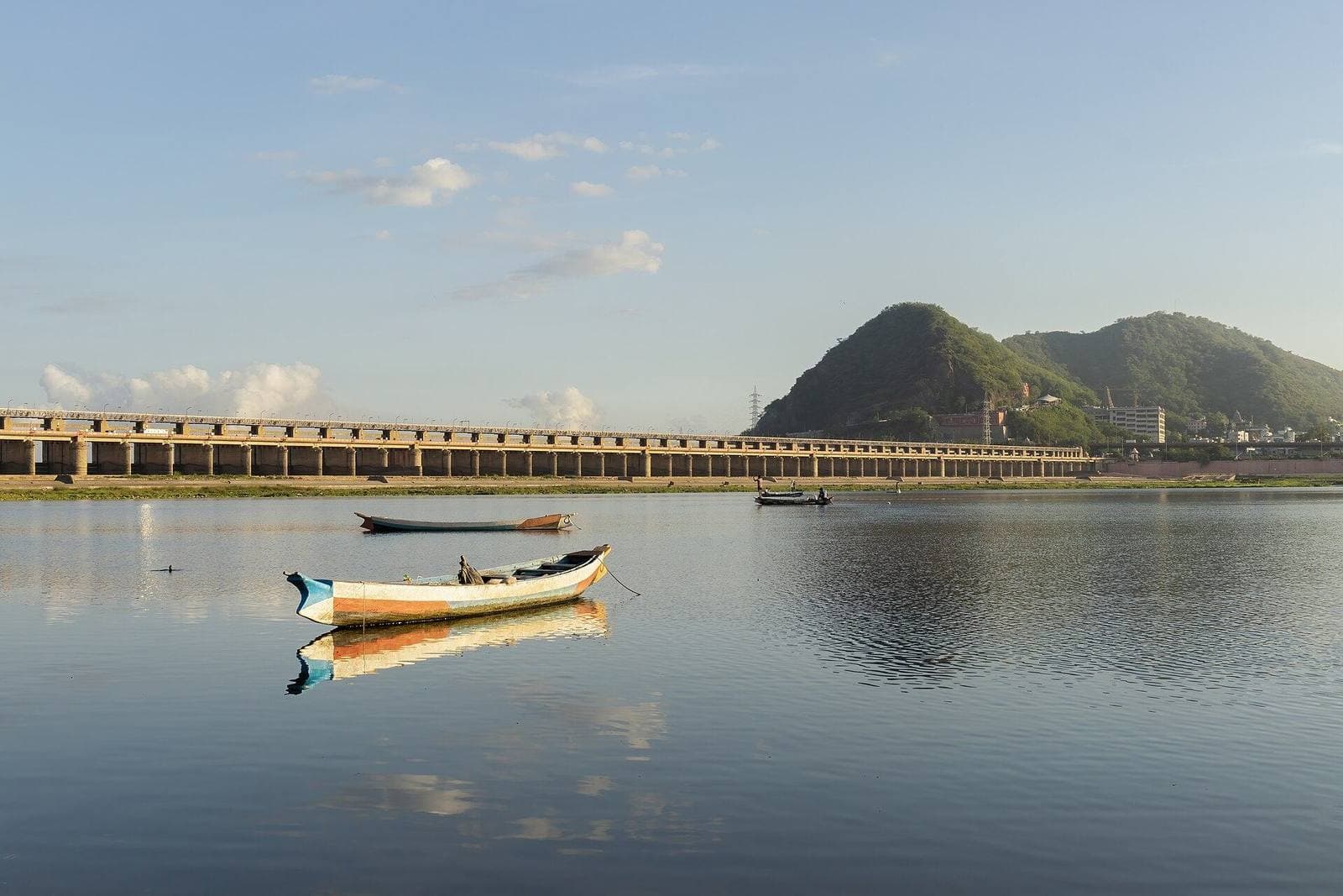 A boat on the Krishna river at Vijayawada, with the barrage and hills behind