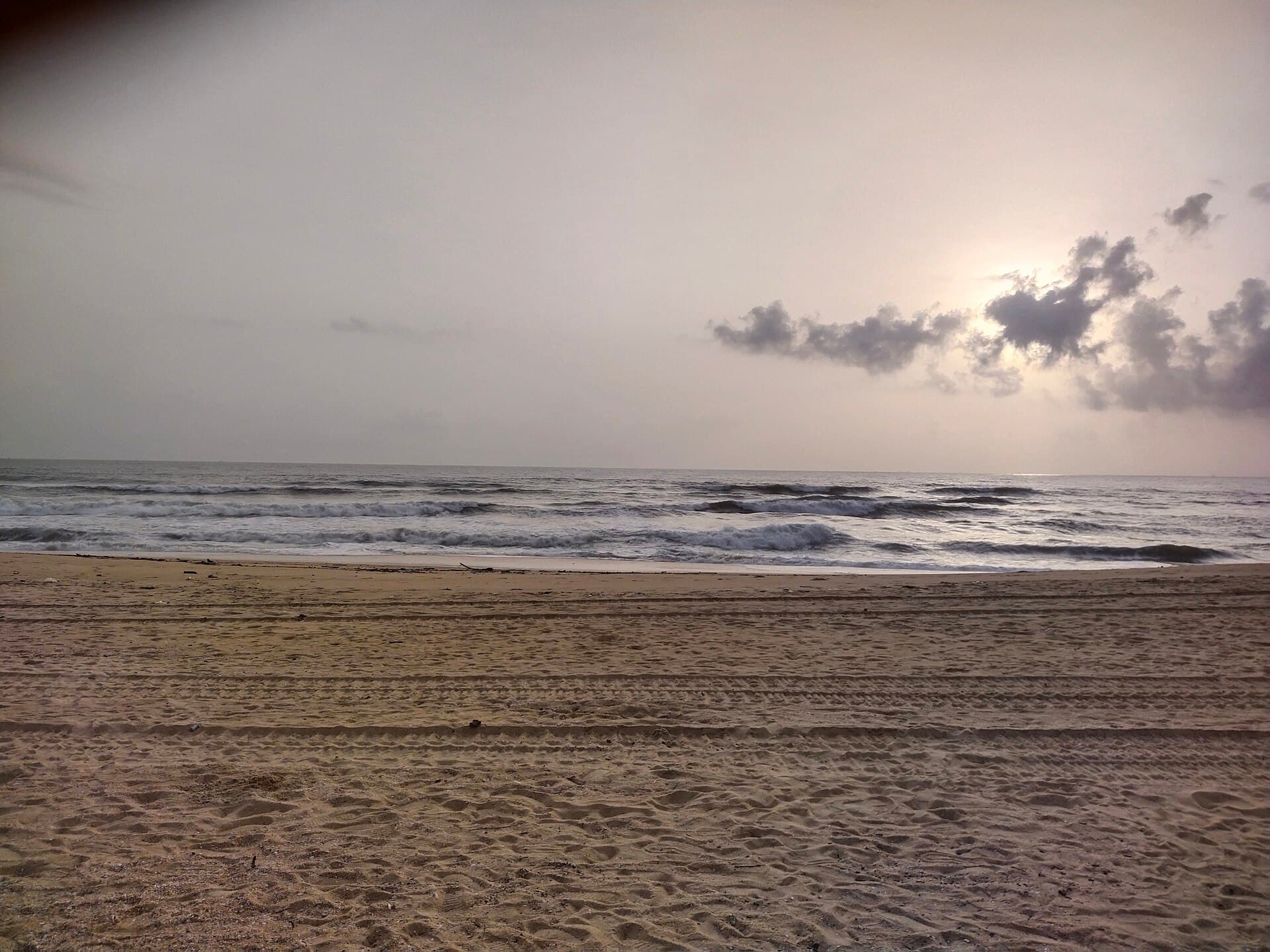 Waves coming in on the sand at Panambur Beach in Mangaluru under a cloudy evening sky