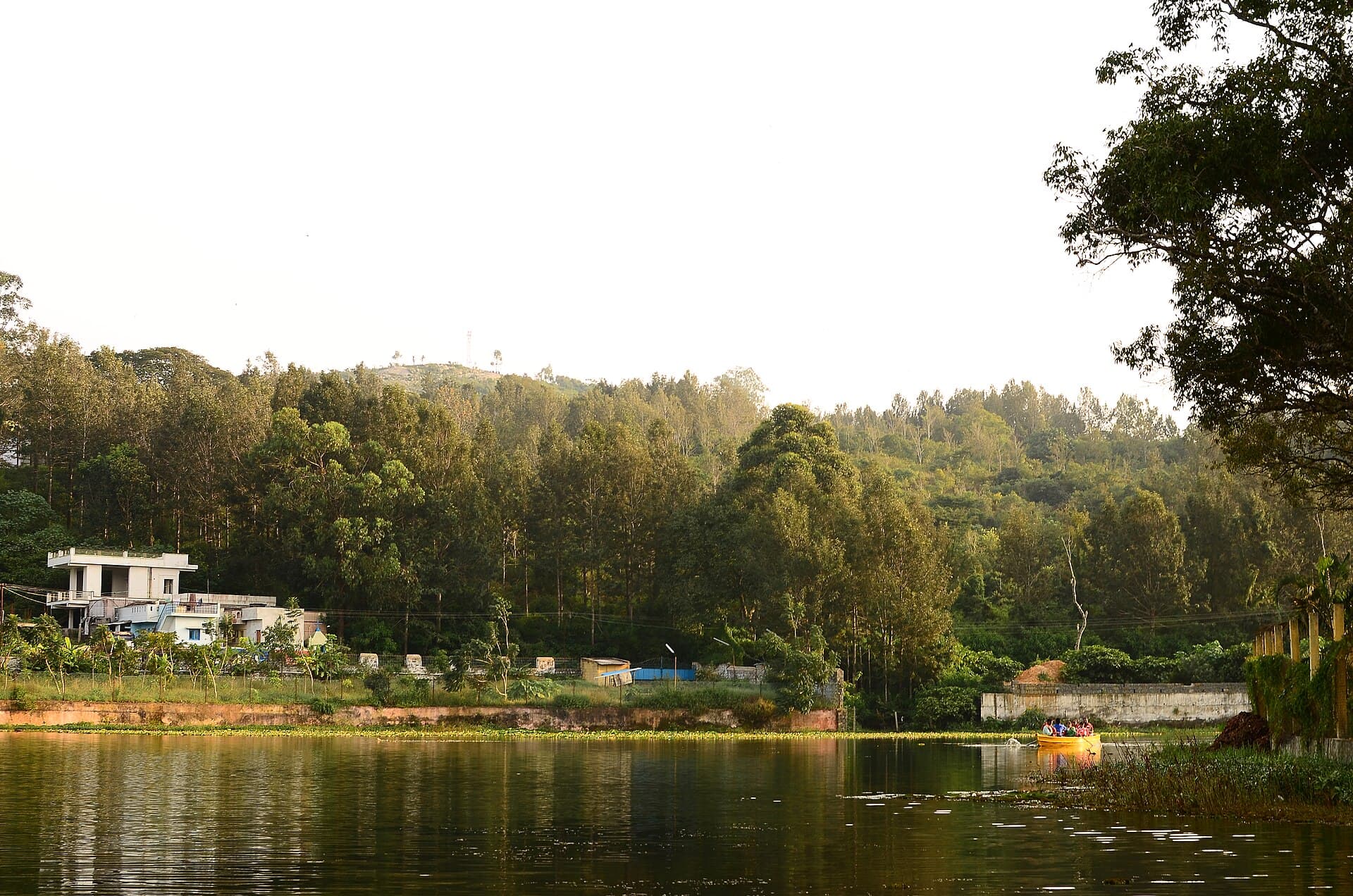 Yercaud Lake with a boat on the water and wooded hills behind